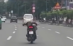 Hai thanh niên nằm dài, điều khiển xe máy lượn lách trên đường