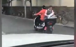 Choáng cảnh bé gái đầu trần vừa ngồi xe máy vừa... làm bài tập