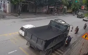 Xe ben vượt phải ở giây cuối đèn xanh, ép xe máy vào lề rồi cán qua