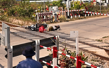 Người đi xe máy tông đổ rào chắn, ngã sát đường ray khi tàu đang đến